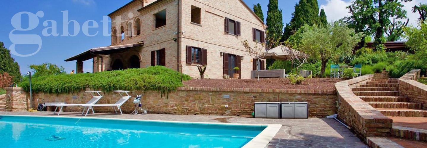 Fotografia principale Immobile[SV04572]: Questa villa di lusso nelle Marche offre un perfetto equilibrio tra tradizione e modernità. Situata in una posizione panoramica, la proprietà è composta da quattro camere da letto, tre bagni e ampi spazi living, distribuiti su tre piani. Il giardino di 5.700 m² ospita una piscina di 12 × 6 metri e una terrazza lounge. A soli 4 km da un paese con tutti i servizi essenziali, la villa è facilmente raggiungibile dalle principali città della regione. Ideale per chi cerca lusso, privacy e vicinanza al mare